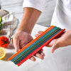 A hand holds a set of colorful silicone chopsticks, including orange, green, and red, on a white surface.