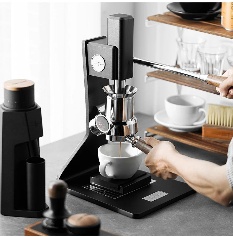 A hand is using a coffee grinder to brew espresso into a ceramic latte cup on a black machine.