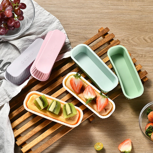 Set aus silikonigen Mini-Backformen in rosa und grün auf einer Holzschneidebrett