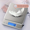A silver digital kitchen scale with a feather placed on the weighing platform.