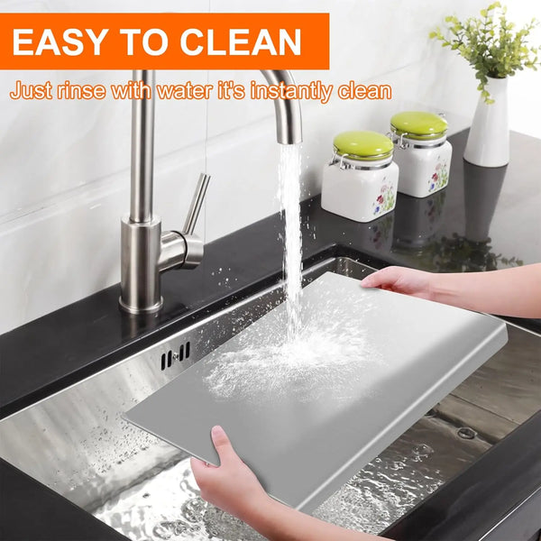 Eine Hand spült ein robustes Edelstahl-Cuttingboard unter einem Wasserhahn ab.