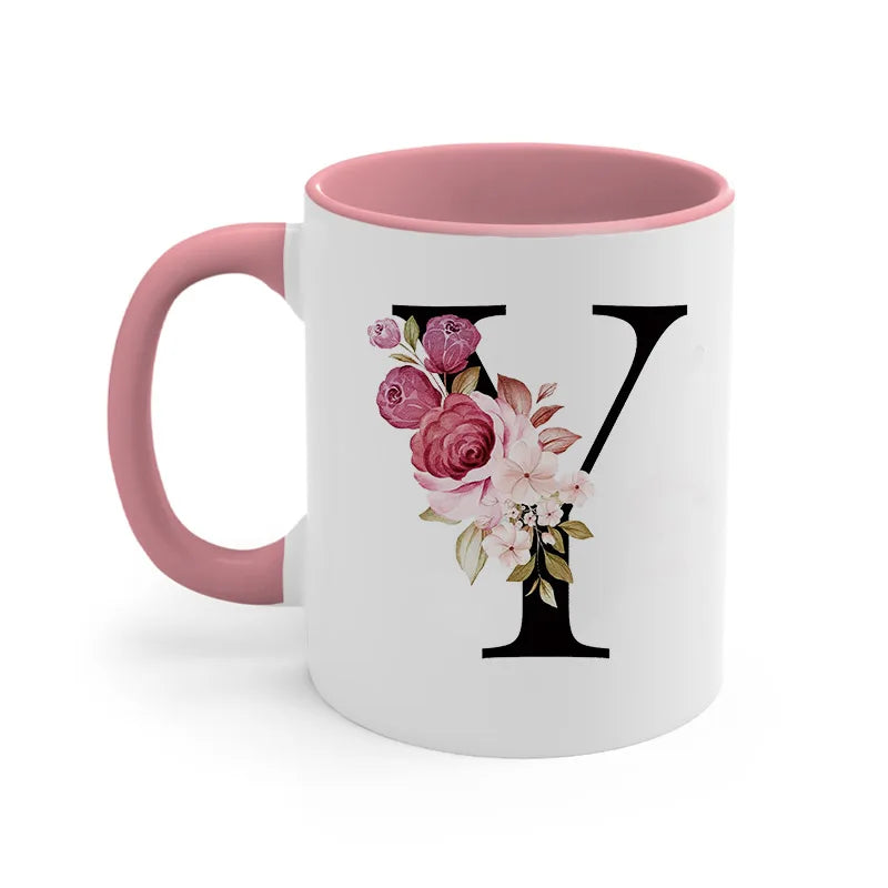 A pink coffee mug with a large black letter Y monogram decorated with pink and white roses.