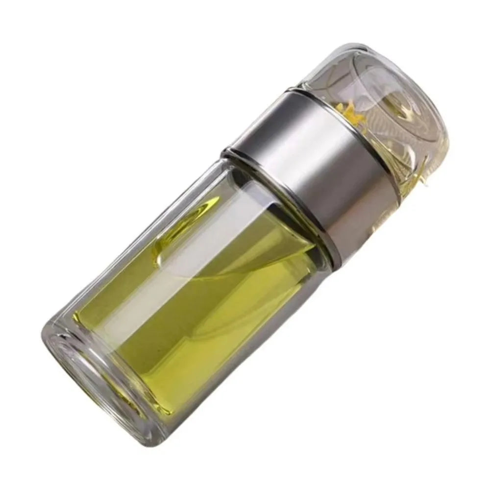 A clear glass tea infuser with a silver cap and yellow liquid inside.
