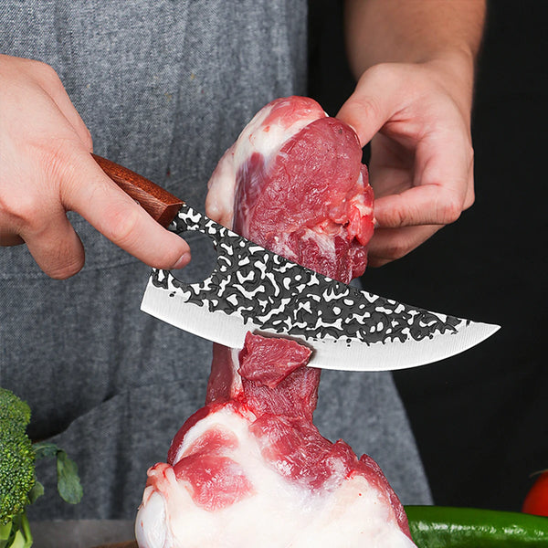 Hände benutzen ein gefälschtes Küchenmesser, um rohes Fleisch zu schneiden, wobei das Messer und das angeschnittene Stück gez
