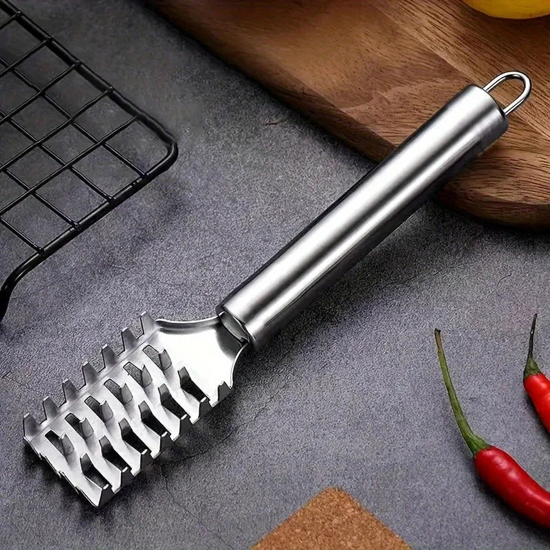A silver stainless steel fish scale remover tool is shown next to a black grill and a red chili pepper.