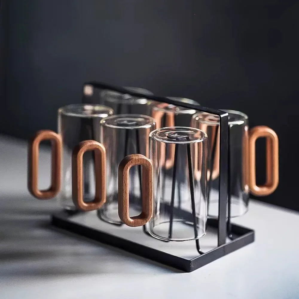Smoke gray glass drinking cups with natural wood handles displayed in a black holder.