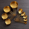 A set of brass measuring cups and spoons arranged on a dark surface.