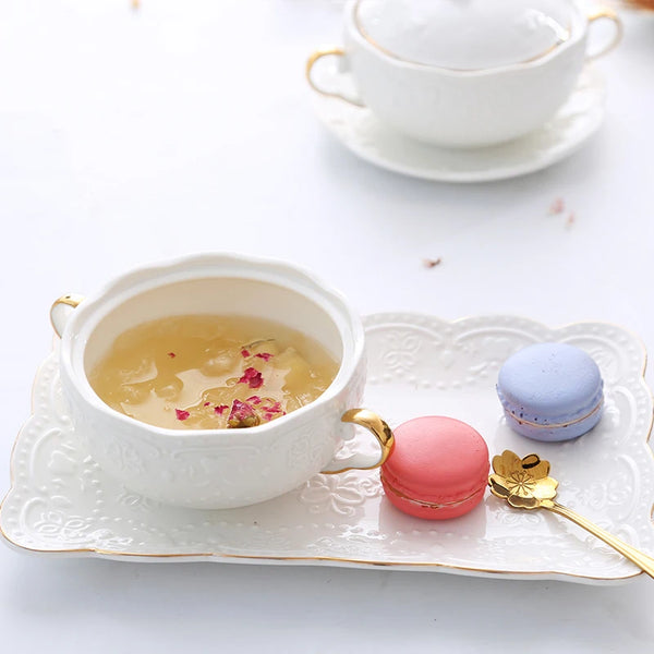 Luxuriöse goldvergoldete Keramikteller für Desserts mit Tee und Macarons auf weißem Teller