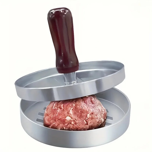 A manual meat patty press tool with a dark purple plunger is shown above a stainless steel meat forming tray.
