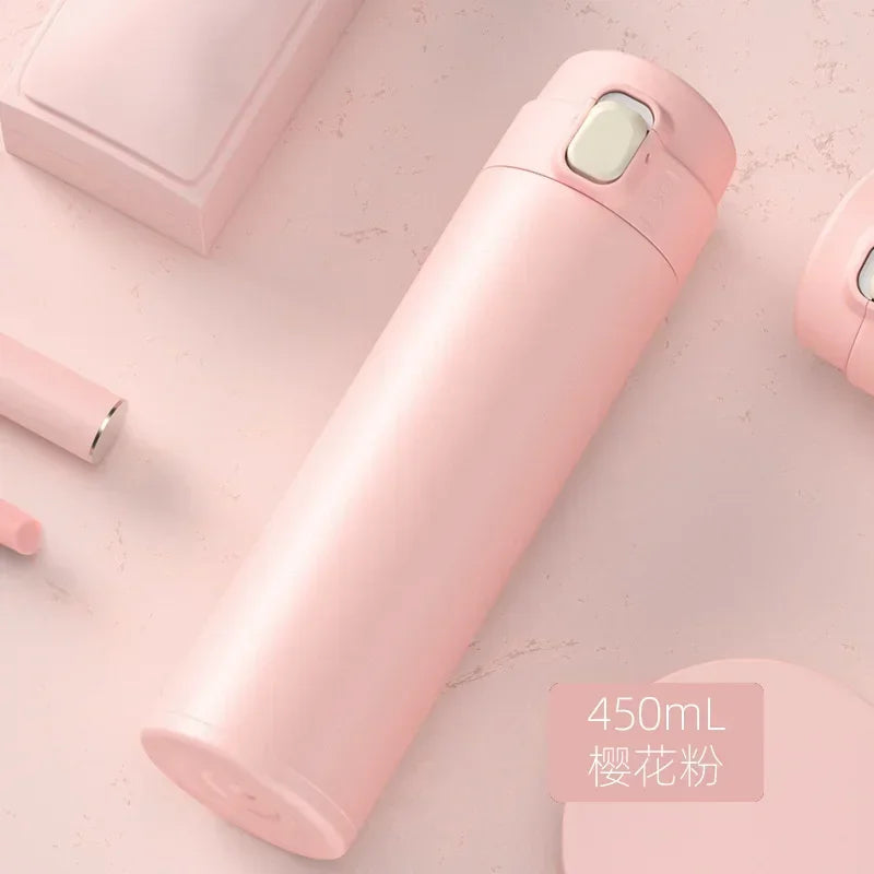 A pink insulated stainless steel vacuum flask lying on a light pink surface.