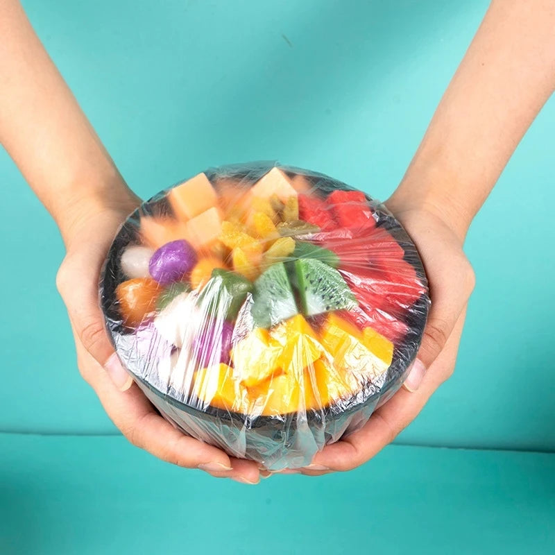 Hands holding a clear plastic container filled with colorful fruit pieces like apples, oranges, and berries.