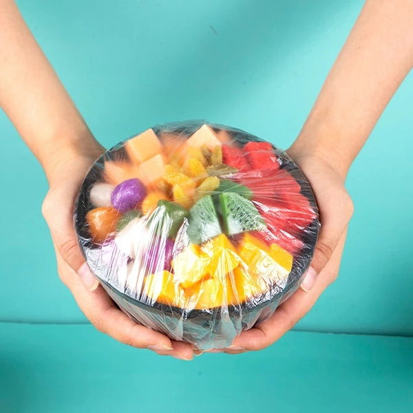 Hände halten einen durchsichtigen Plastikbehälter mit bunter Frucht wie Äpfeln, Orangen und Beeren.