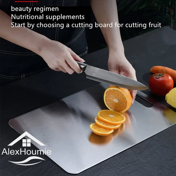 A hand is using a knife to cut fruit on a stainless steel cutting board.