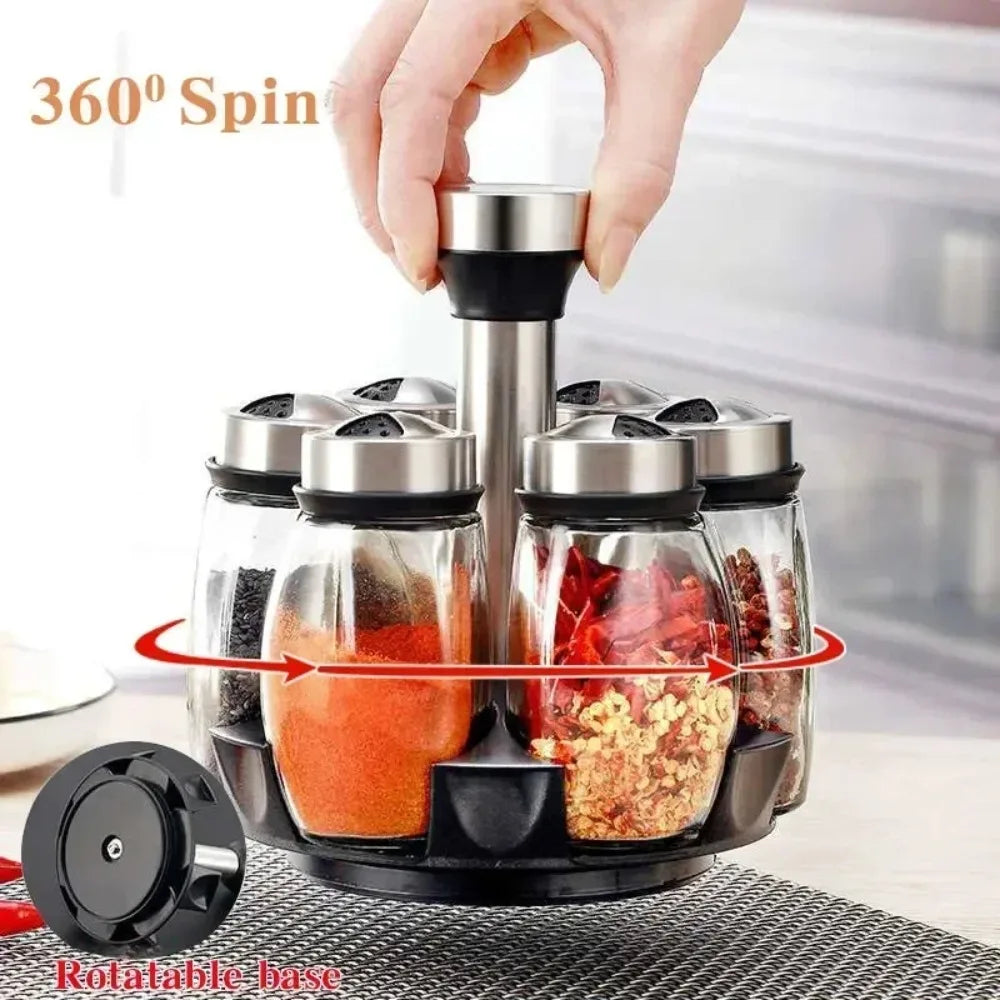 A hand is rotating a black glass spice jar set on a rotating base for kitchen organization.