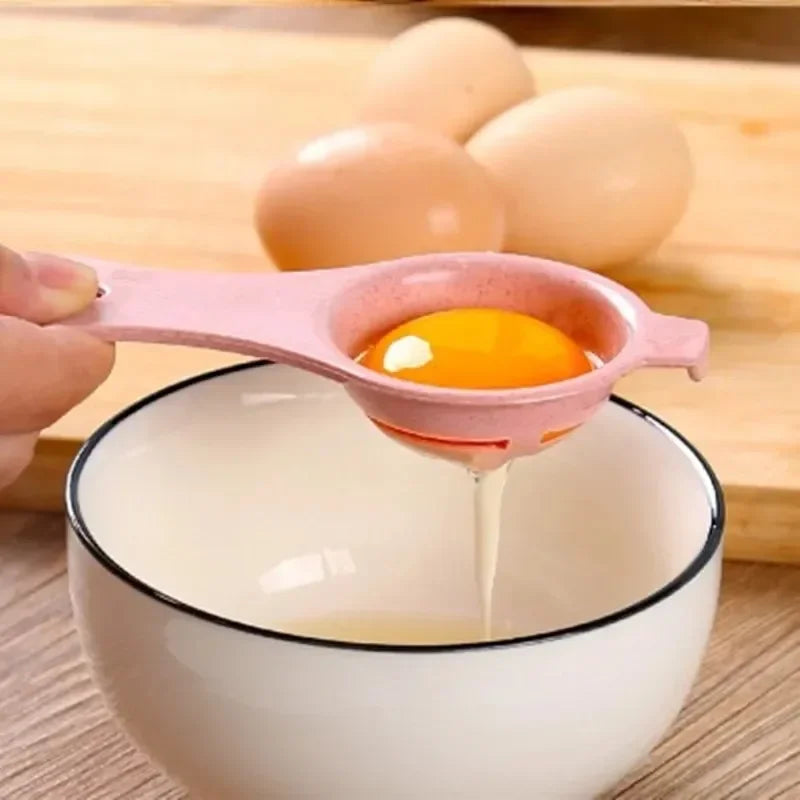 A pink silicone egg separator is dripping liquid from a raw egg into a white bowl, with several whole eggs visible in the bac