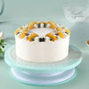 A white cake decorated with yellow citrus slices and white frosting swirls on a light blue platter.