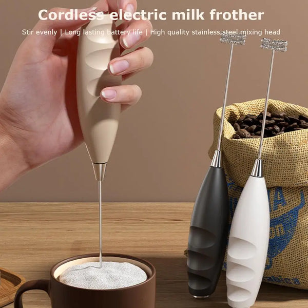 Eine Hand hält einen kabellosen Milchaufschäumer-Paddel in eine Milchtasse.