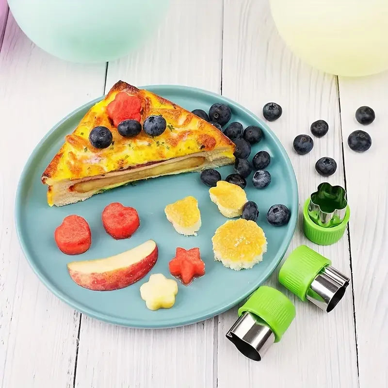 A plate features a slice of fruit tart and various fresh fruits arranged around it, with stainless steel molds nearby.