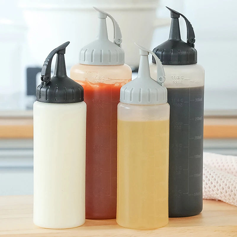 Three squeeze seasoning dispenser bottles in white, orange, and dark gray standing on a wooden surface.