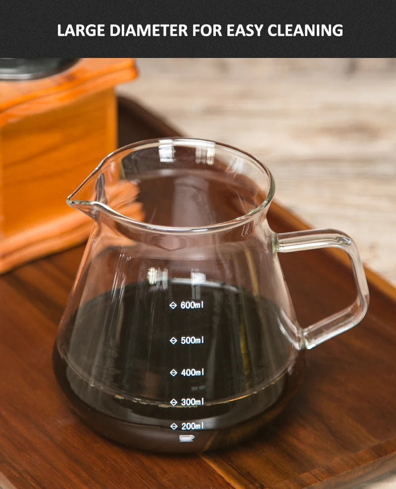 A clear glass pour over coffee pot with volume markings sits on a wooden surface.