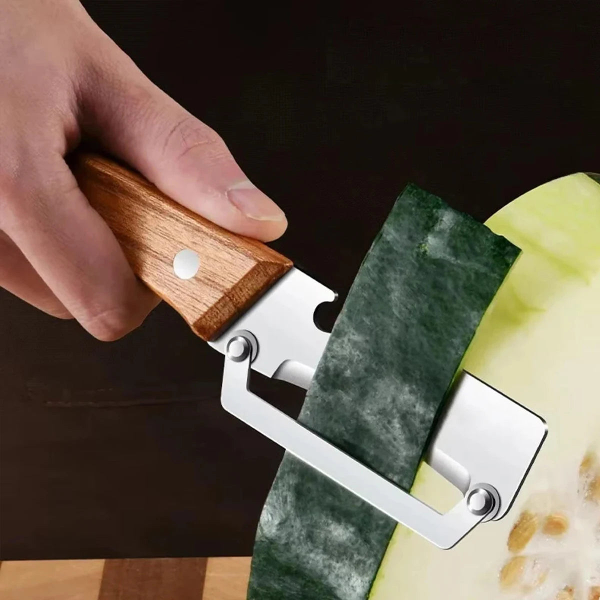 A hand is holding an ergonomic wooden vegetable peeler with a silver blade against a green vegetable.