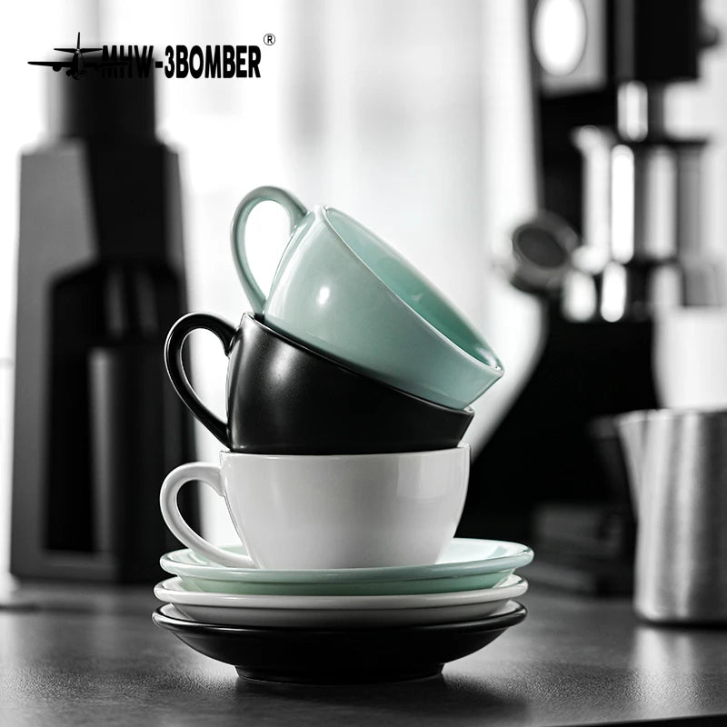 A stack of black and mint green ceramic latte cups and saucers on a dark surface.