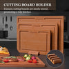 A wooden cutting board holder with three slots for storing cutting boards, set against a kitchen background.