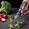 A hand uses professional stainless steel kitchen scissors to cut broccoli florets on a dark surface.