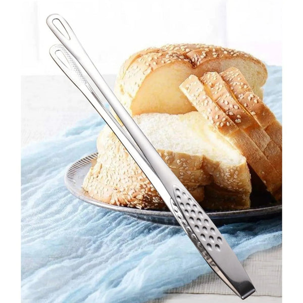 Ein Paar Edelstahl-Grillzangen auf einem hellblauen Tuch neben geschnittenem Brot.