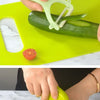 Hands are preparing food using a green all-functional fruit and vegetable cutting set on a yellow cutting board.