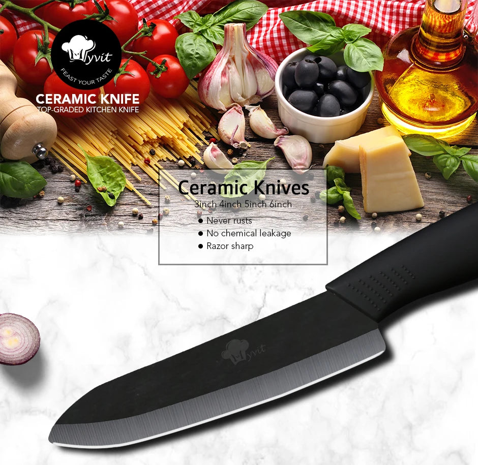 A black ceramic chef knife is displayed next to fresh produce and a block of cheese on a white marble surface.