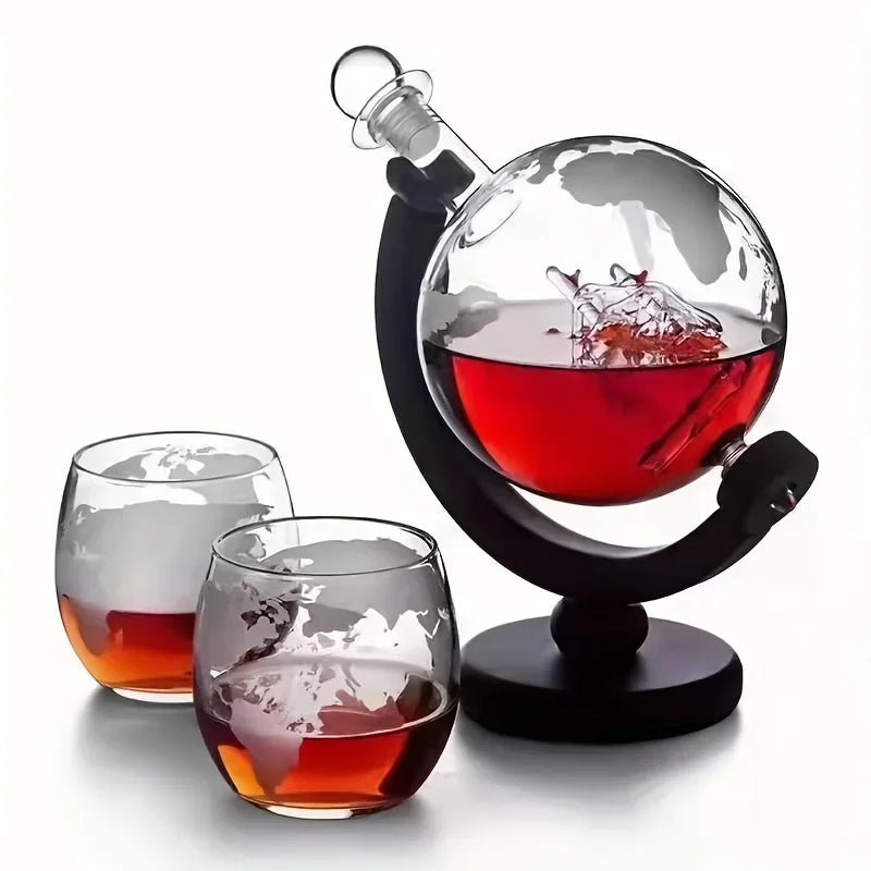 Un elegante juego de decantador con una esfera de vidrio sobre un soporte y dos vasos de whisky.