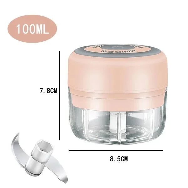 A clear plastic mini food chopper and grinder with a pink lid and a silver attachment tool.