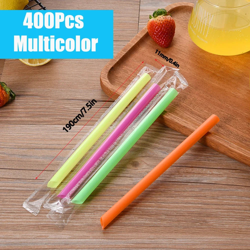 A set of four multicolored plastic drinking straws in yellow, pink, green, and orange are displayed on a wooden tray.
