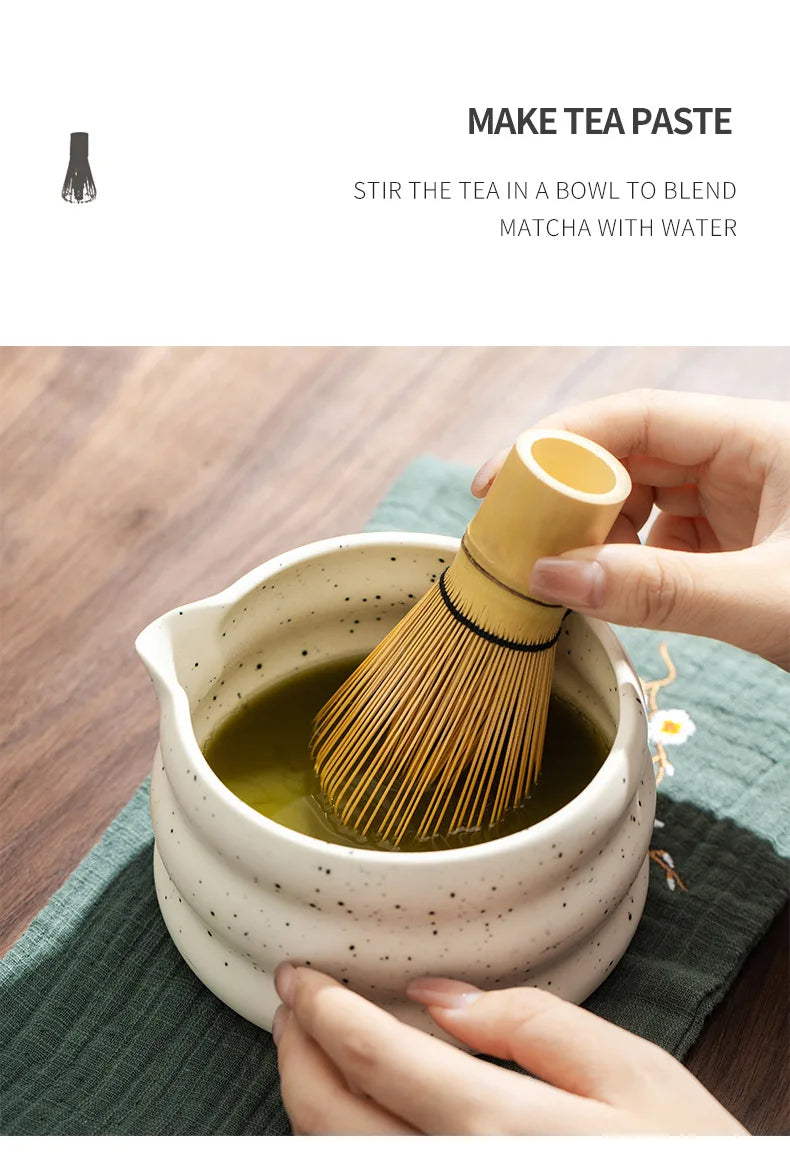 Hands stir green matcha tea in a ceramic bowl using a bamboo whisk.