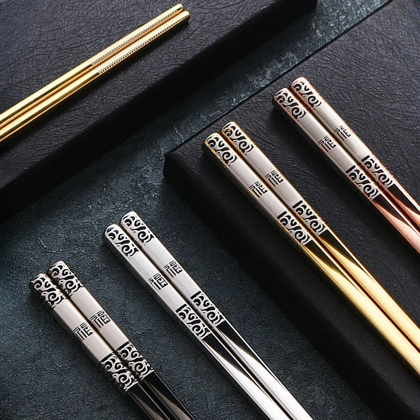 Set wiederverwendbare Edelstahl-Stäbchen in verschiedenen Finishes und Winkeln auf dunkler Oberfläche.