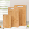 A set of three light wood bamboo kitchen cutting boards displayed on a white surface.