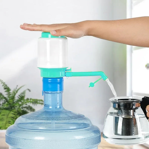 Eine Hand bedient eine manuelle Eimerwasserpumpe und gießt Wasser in ein Glasgefäß.