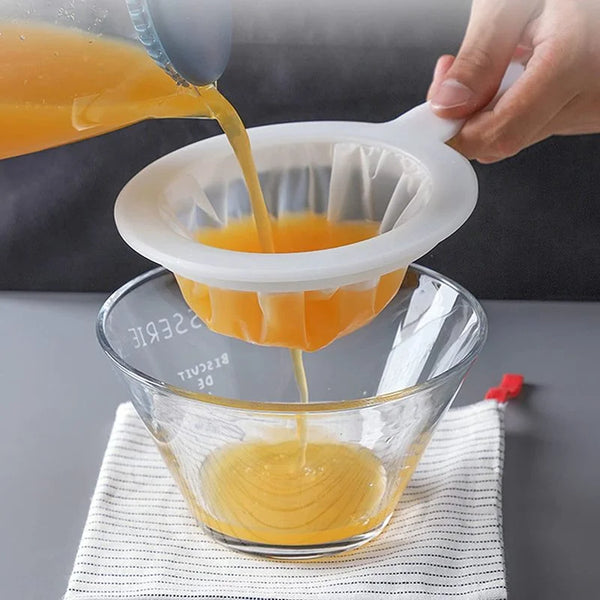 Eine Hand gießt Orangensaft aus einem Mehrfachsieb in eine Glasschale.