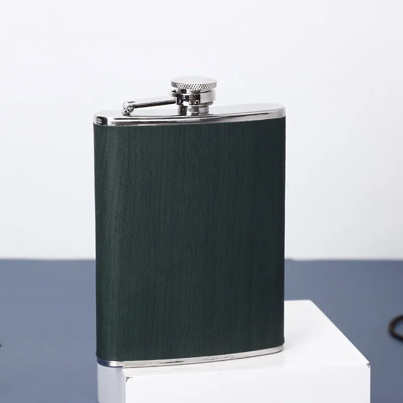 Una botella de acero inoxidable verde oscuro con tapa plateada sobre una superficie blanca.