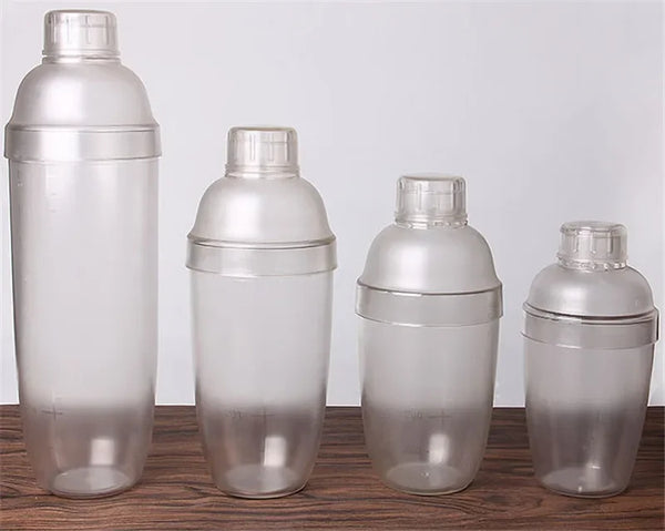 Ein Set klarer Plastik-Cocktail-Shaker mit Schraubverschluss auf einer Holzoberfläche.