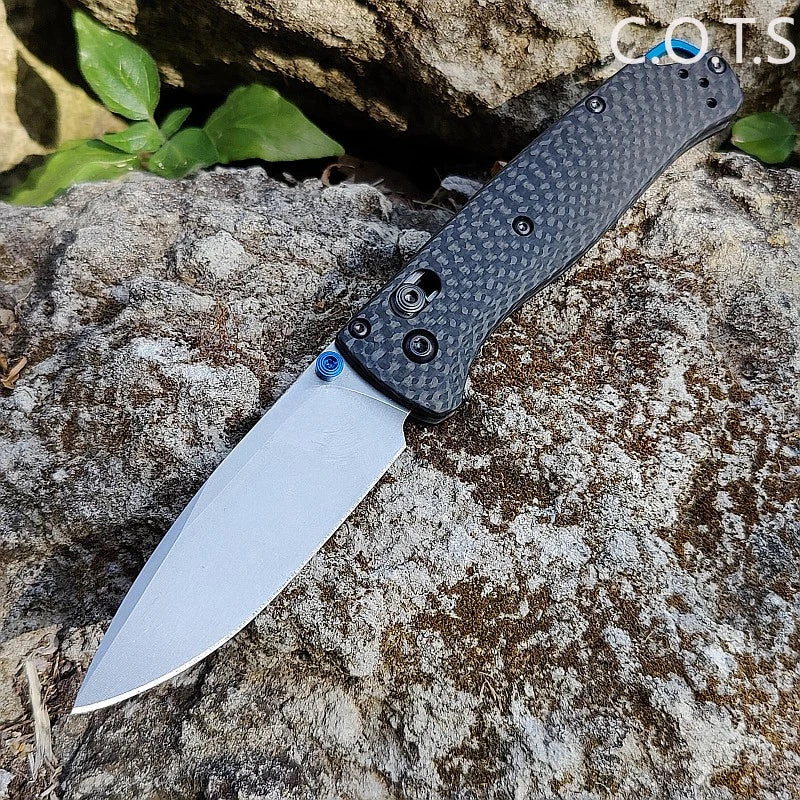 A premium folding utility knife with a black textured handle and silver blade resting on a rough rock.