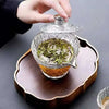 An elegant glass tea set featuring a clear glass teapot and lid resting on a wooden tray.