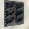 A black silicone dinosaur ice cube tray set with various dinosaur shapes.