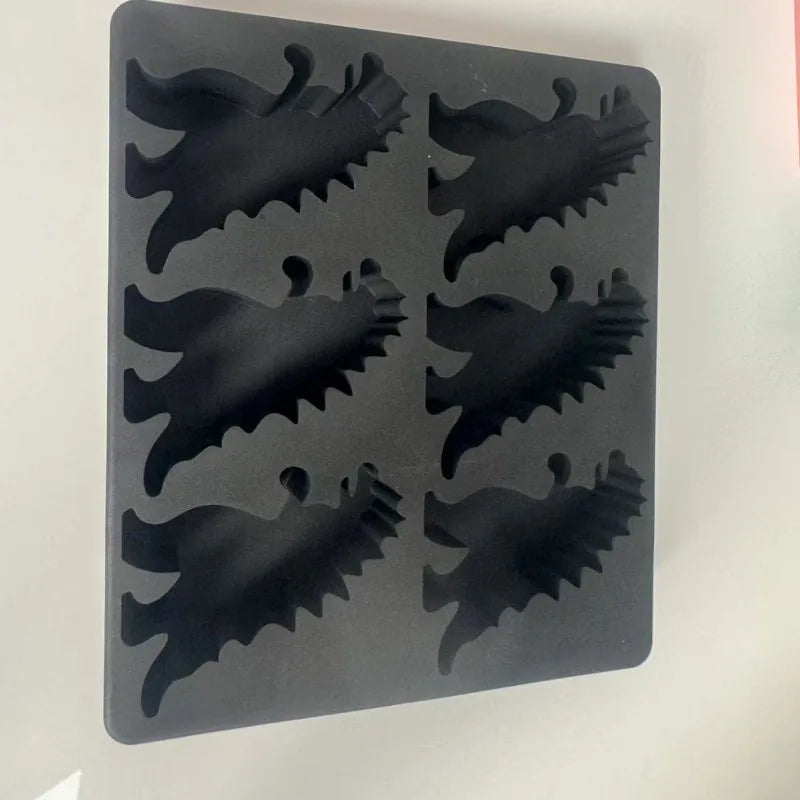 A black silicone dinosaur ice cube tray set with various dinosaur shapes.