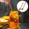 A glass of orange juice with slices, being served by a wooden spoon against a dark background.