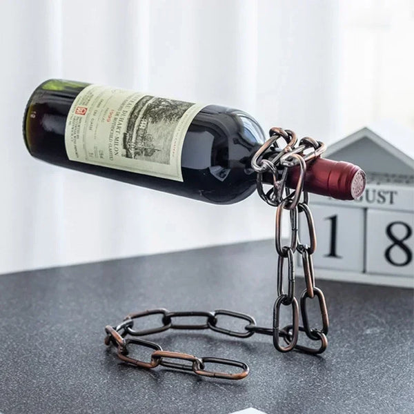 A dark wine bottle with a label is suspended by a metal chain, used as home bar decor.