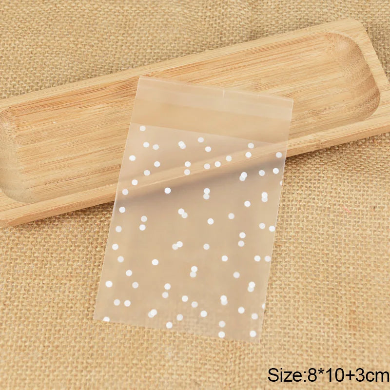 Transparent dot candy cookie bags are shown resting on a wooden tray and burlap fabric.