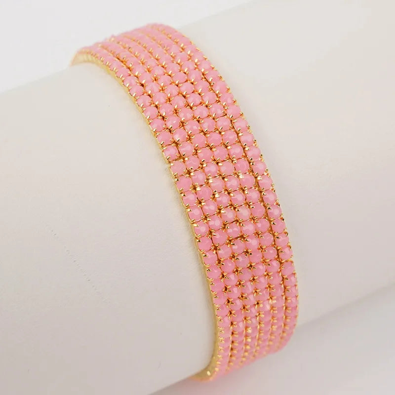Pink acrylic elastic bracelet with gold accents stacked on a white wrist.