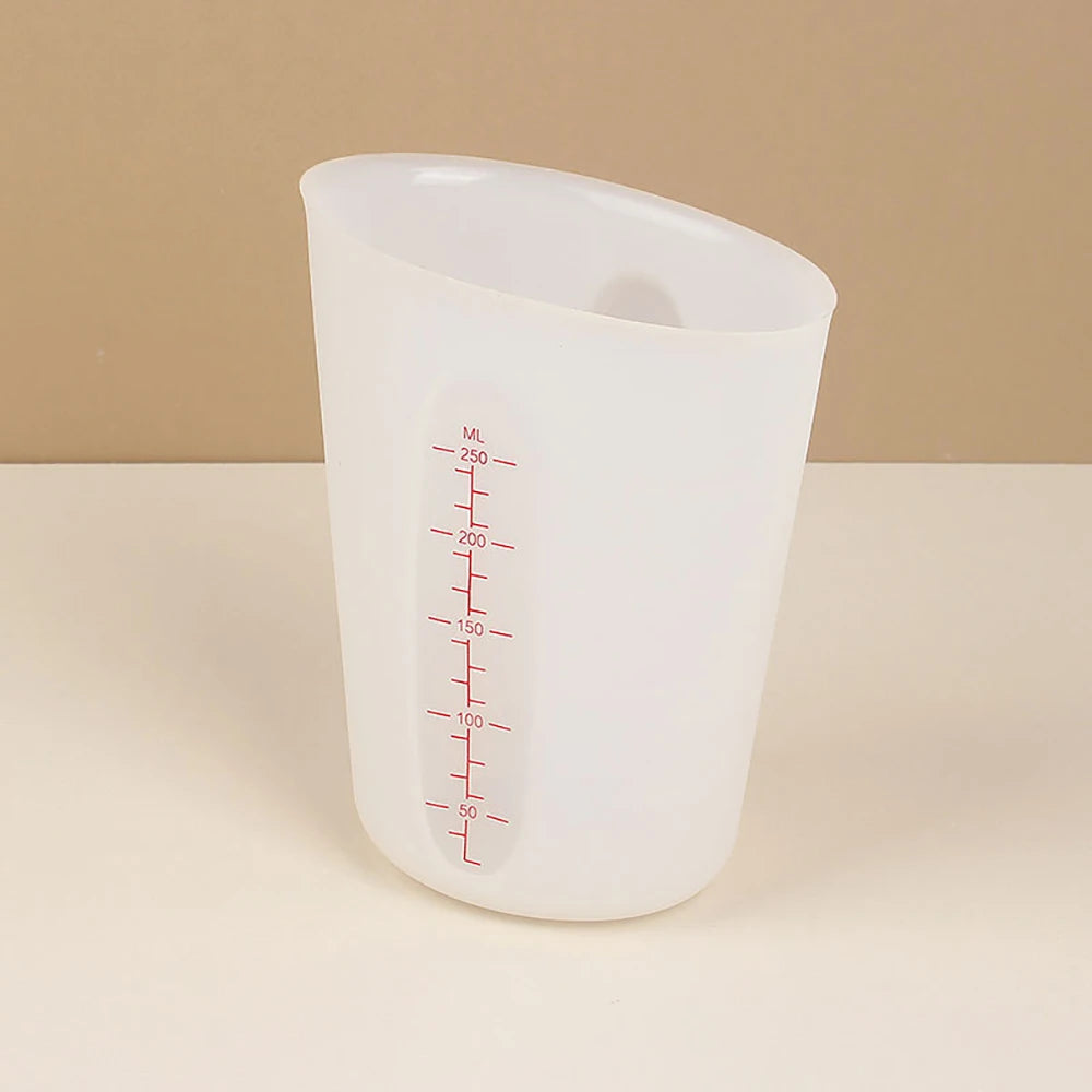 A clear silicone measuring cup with red markings for volume measurement is shown on a light surface.